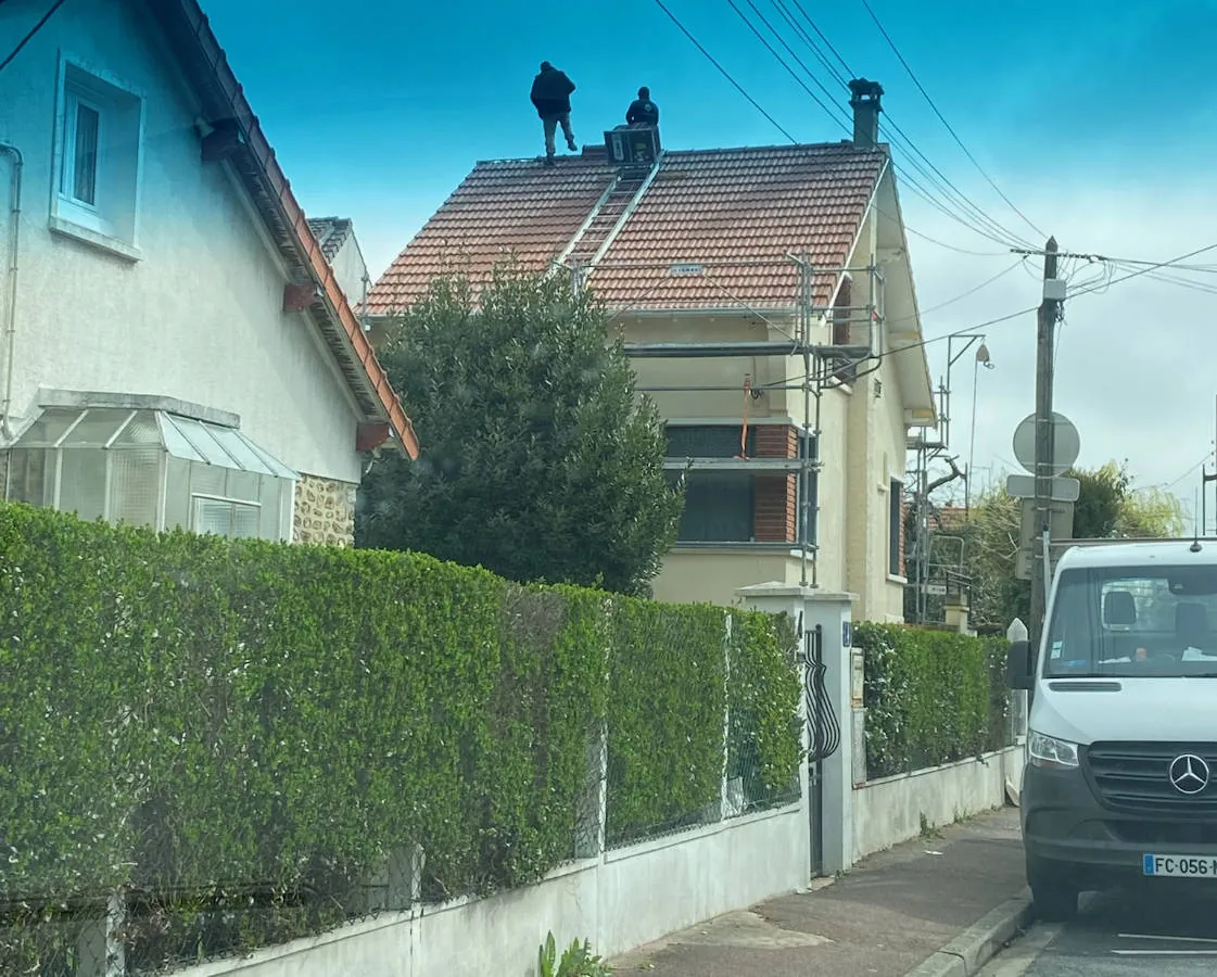 Véhicule Simonard devant une maison dont la toiture est en rénovation — M. Simonard, couvreur à Montreuil